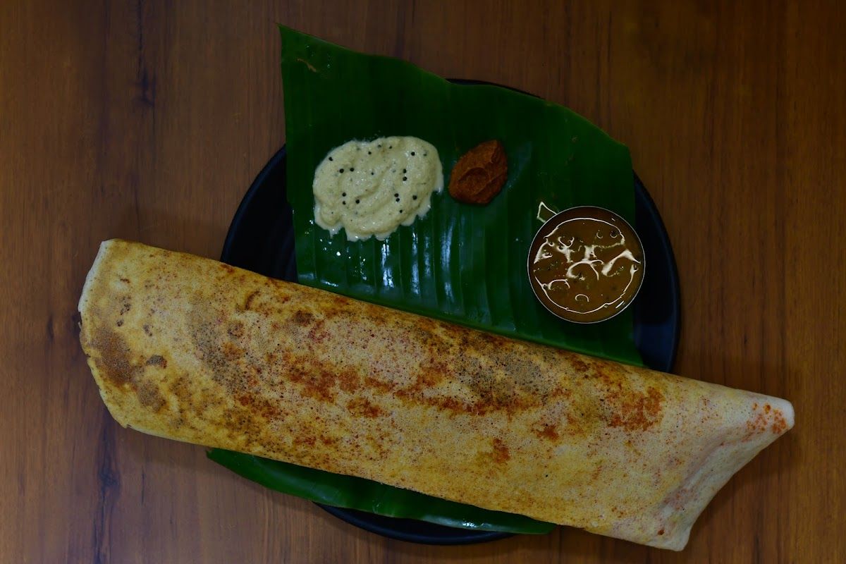 Masala dosa on a banana leaf with sambhar and chutneys