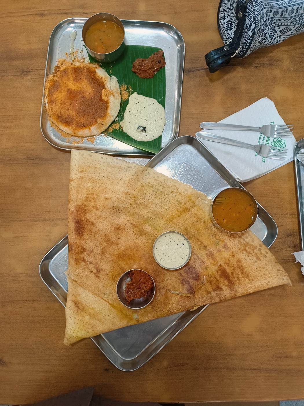 Dosa served on steel plate with chutneys